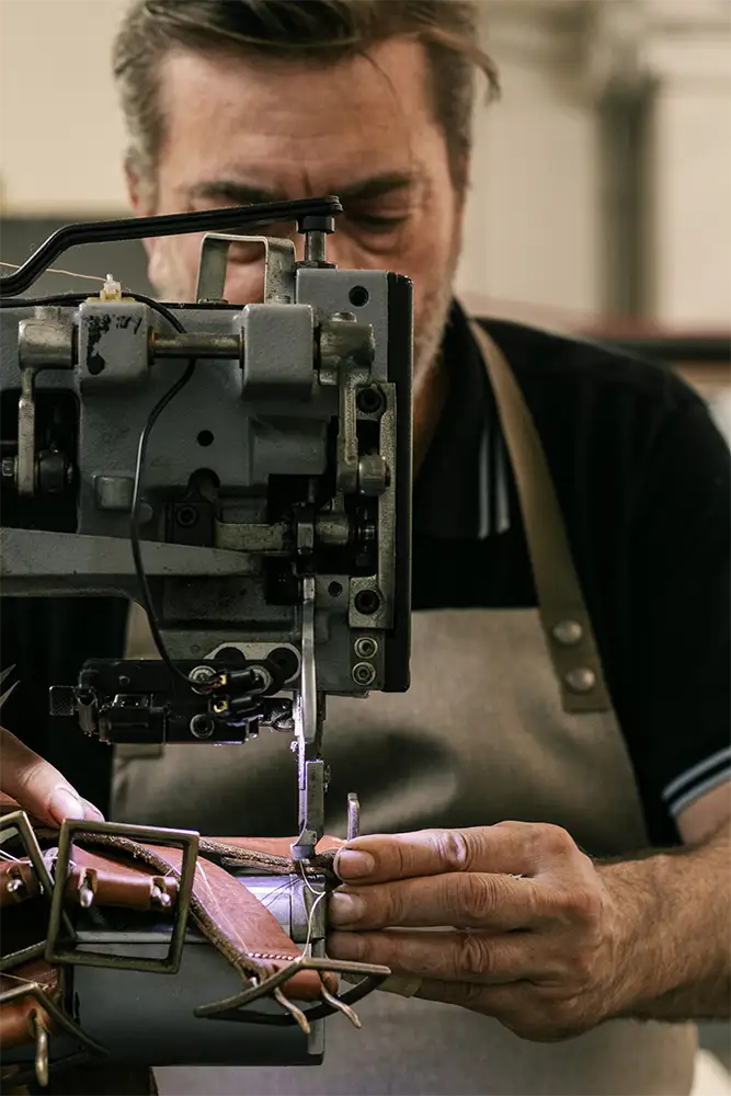 Artisanal belt factory Made in Italy - Balzani - the photo shows the owner Andreas stitching a belt using a manual sewing machine